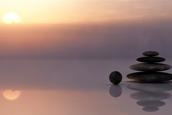 Piedras en equilibrio junto al agua al atardecer, imagen de la terapia para el estrés y el burnout en Zaragoza